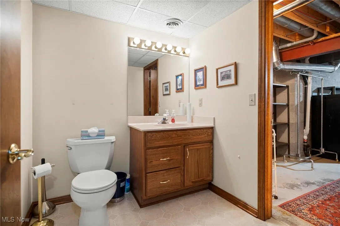Bathroom featuring a drop ceiling, vanity, heating fuel, and light tile patterned floors