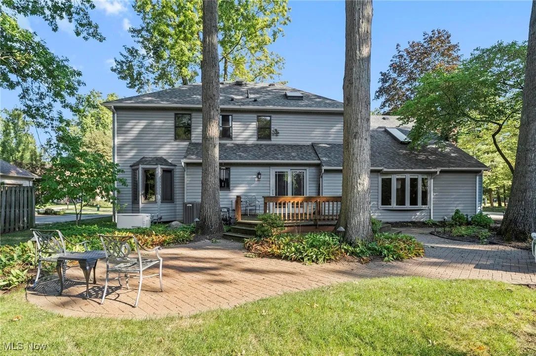 Back of property with a patio area, a lawn, a wooden deck, and a shingled roof