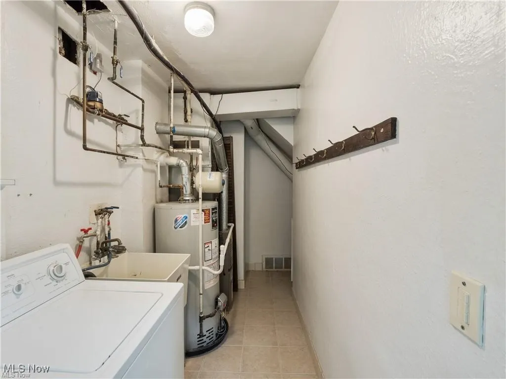 Laundry room featuring washer / clothes dryer, secured water heater, and light tile patterned flooring
