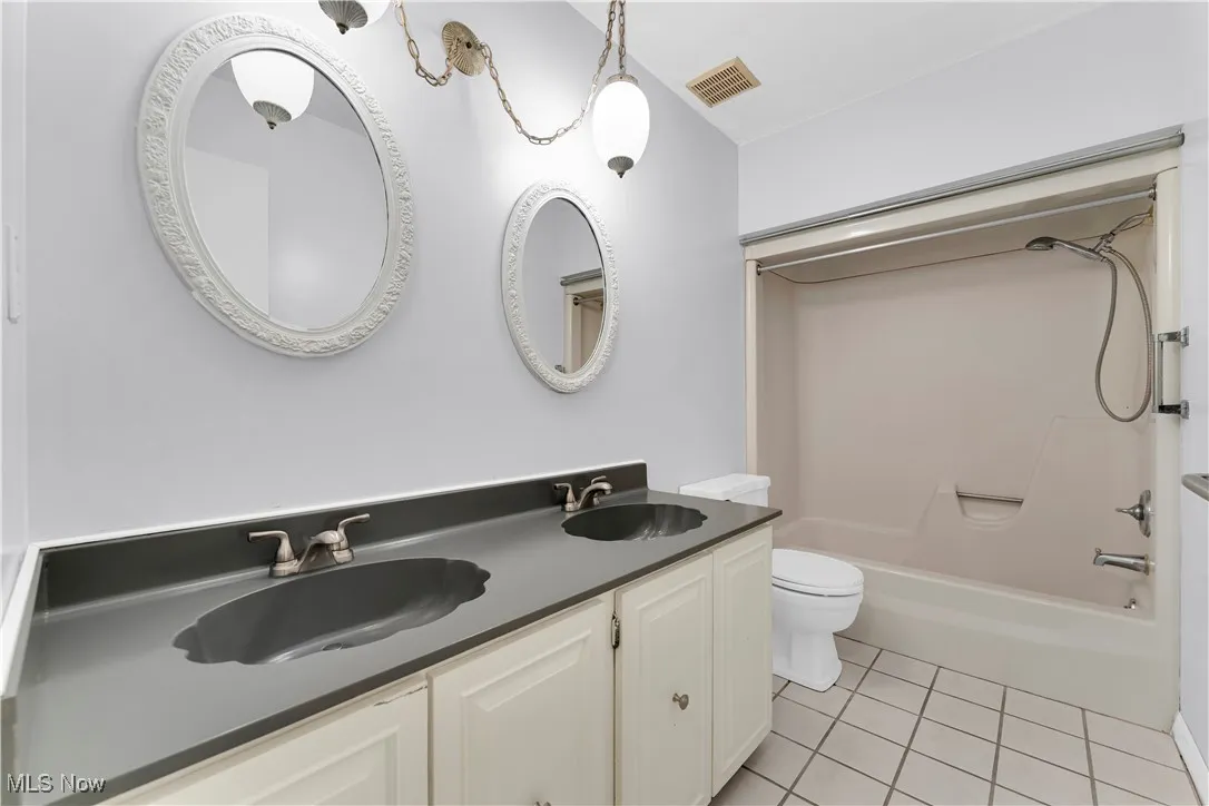 Full bathroom featuring light tile patterned floors, shower / tub combination, and double vanity