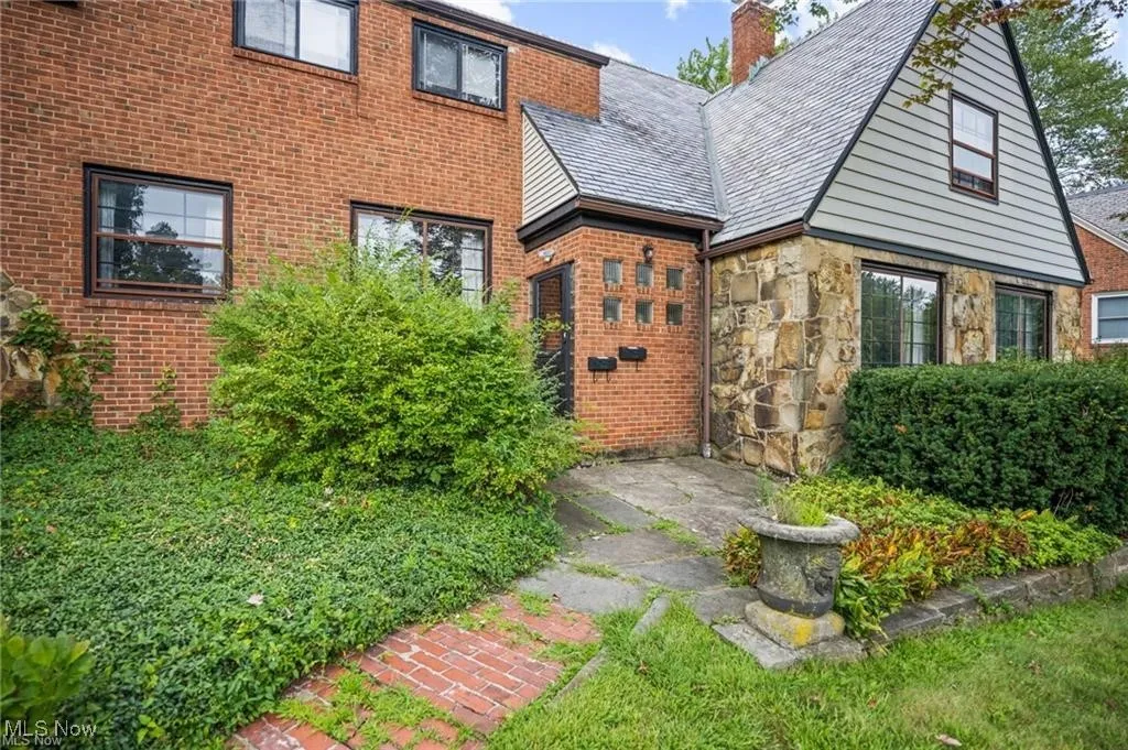 View of exterior entry featuring a chimney, stone siding, and brick siding