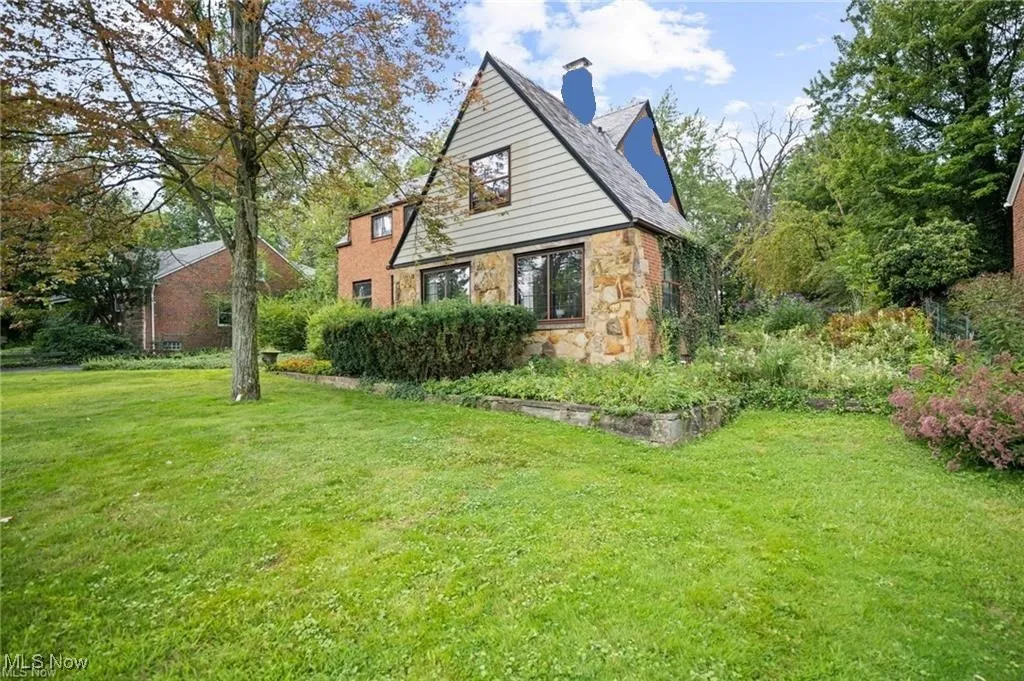 Back of property featuring stone siding, a yard, and a chimney