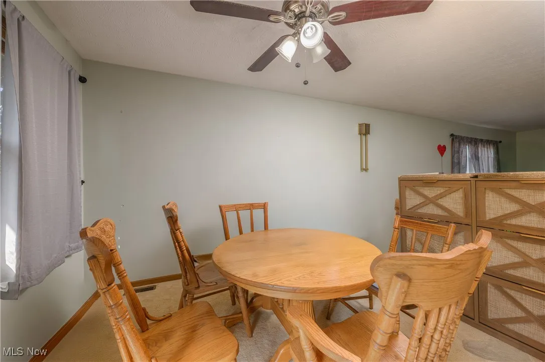 Dining area featuring a textured ceiling, carpet flooring, and a ceiling fan