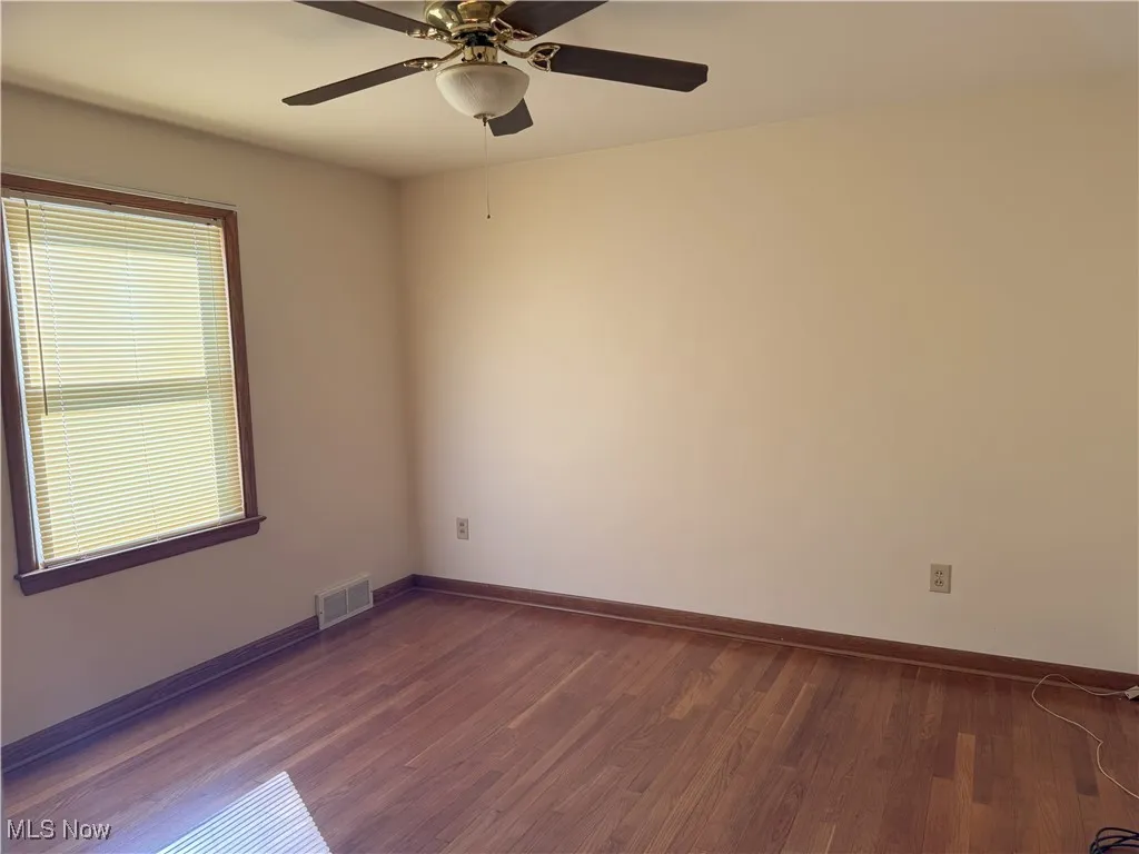 Spare room featuring dark wood-type flooring and ceiling fan