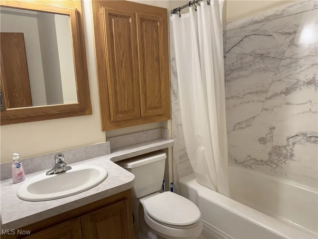 Full bath featuring shower / bathtub combination with curtain and vanity