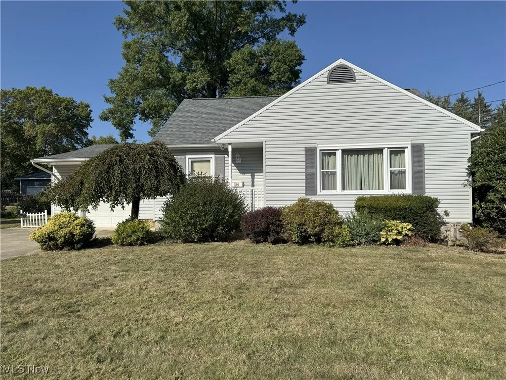 View of front of home featuring a front lawn, roof with shingles, and an attached garage