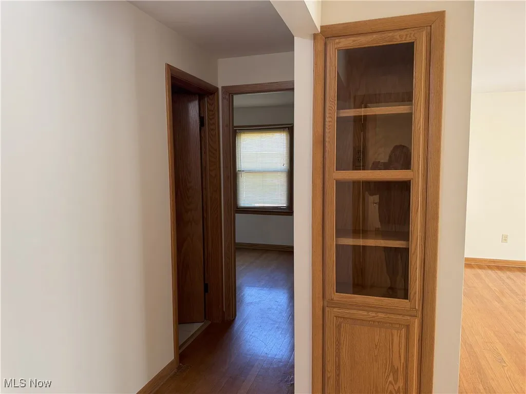 Hallway featuring dark wood-style flooring and baseboards