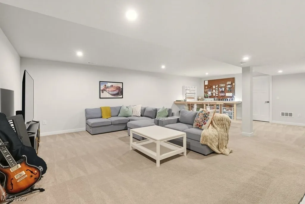 Living area with light colored carpet and recessed lighting