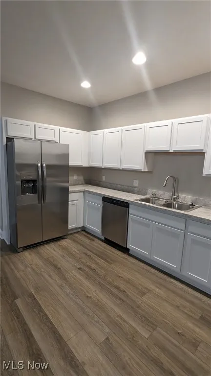 Kitchen with stainless steel appliances, dark wood-style floors, white cabinets, recessed lighting, and light countertops