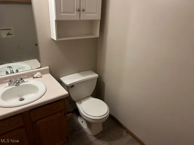 Half bath with vanity and wood-style finished floors
