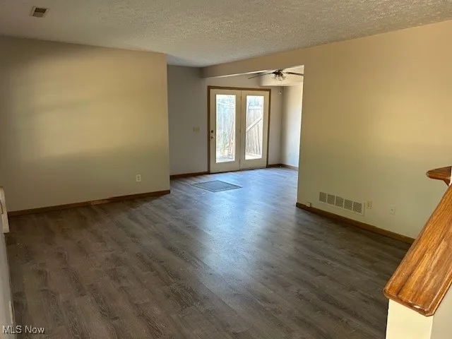 Spare room with dark wood-style flooring, a textured ceiling, ceiling fan, and french doors