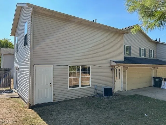 Back of property featuring a garage, a yard, and driveway