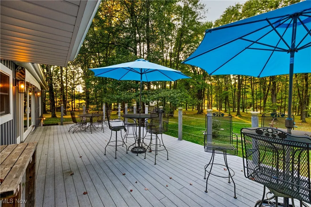 Wooden deck featuring outdoor dining space and a lawn