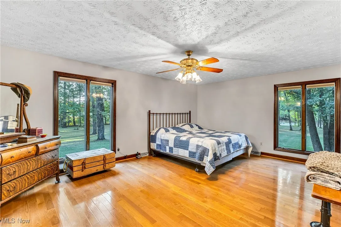 Bedroom with light wood finished floors, ceiling fan, and a textured ceiling