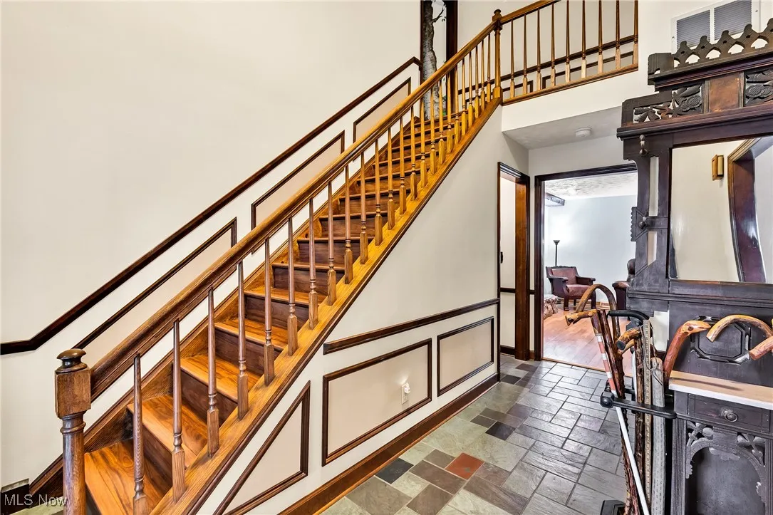Staircase with a towering ceiling and stone tile floors
