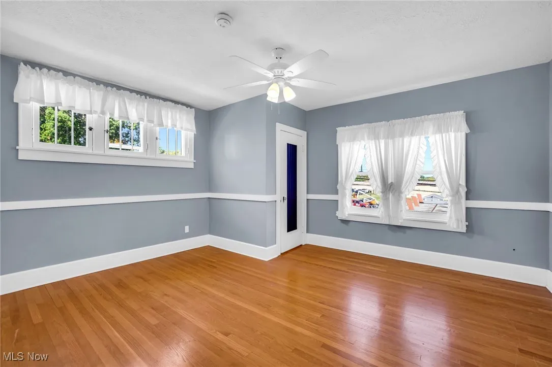 Unfurnished room with healthy amount of natural light, wood finished floors, a ceiling fan, and a textured ceiling