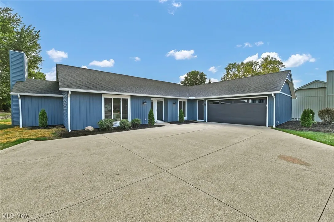 Single story home featuring roof with shingles, a chimney, concrete driveway, and an attached garage