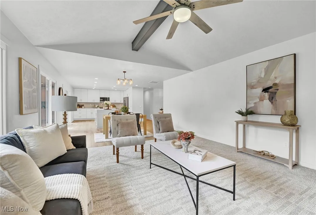 Living area featuring a chandelier, light carpet, and ceiling fan