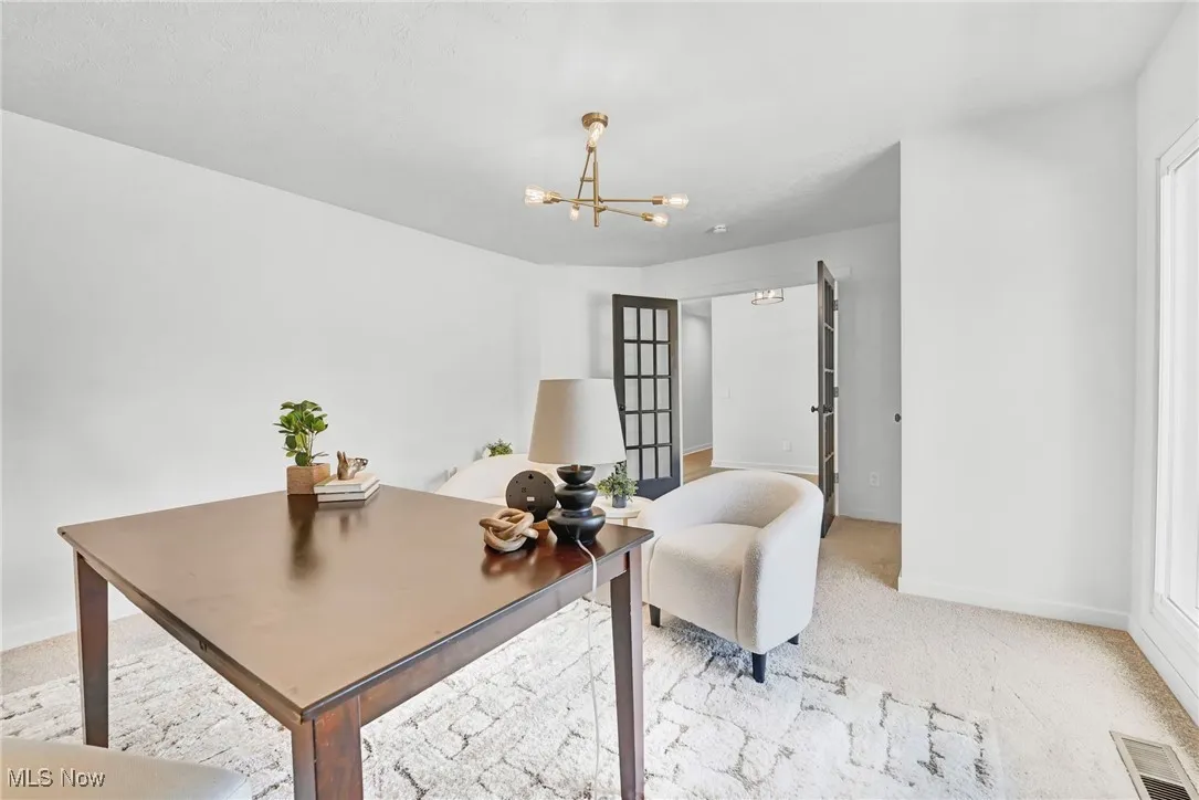 Office area with a chandelier and light colored carpet