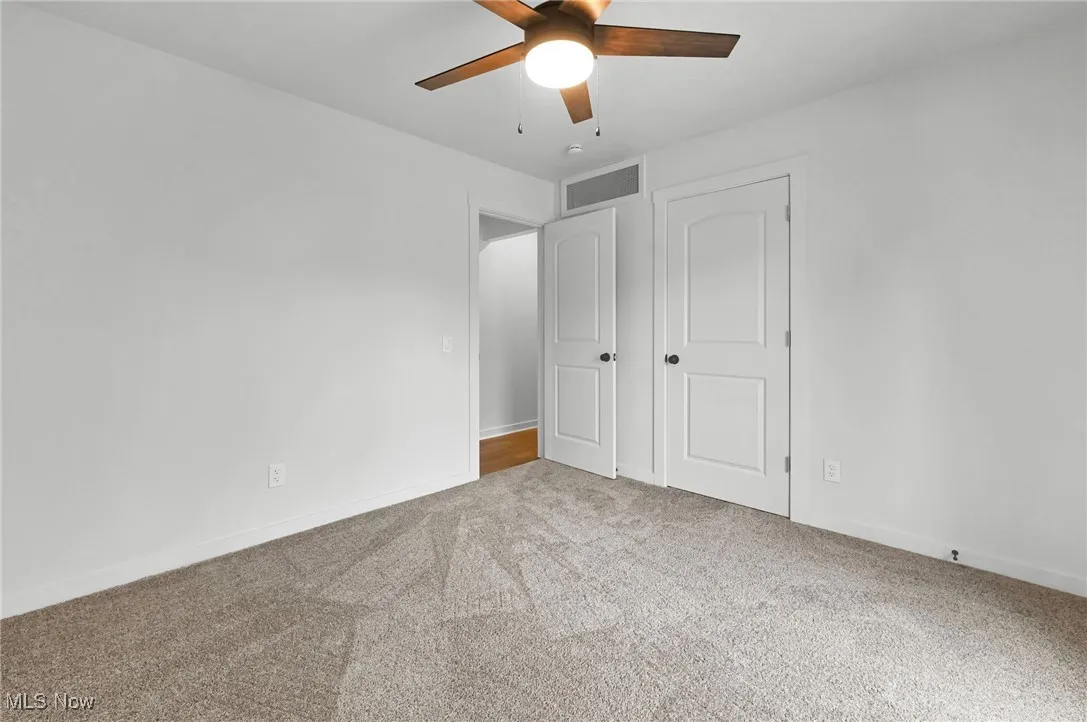 Unfurnished bedroom with light carpet, a ceiling fan, and a closet