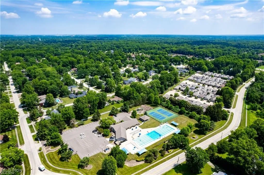 Aerial view of residential area featuring a pool and a heavily wooded area