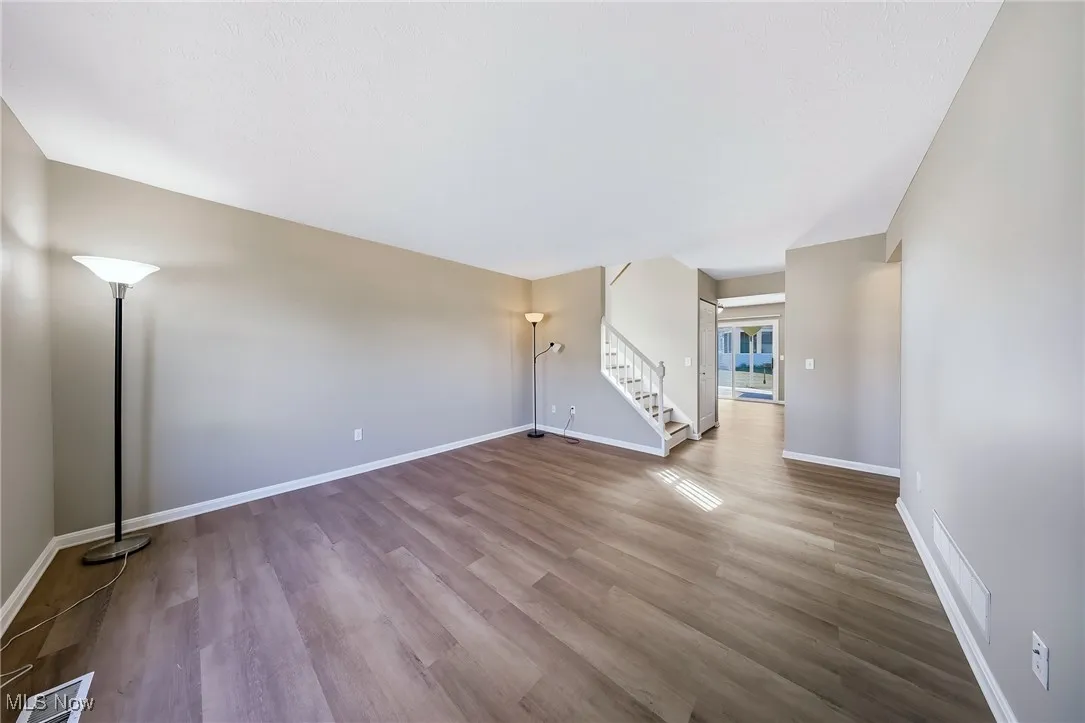 Unfurnished living room featuring stairs and light wood-type flooring
