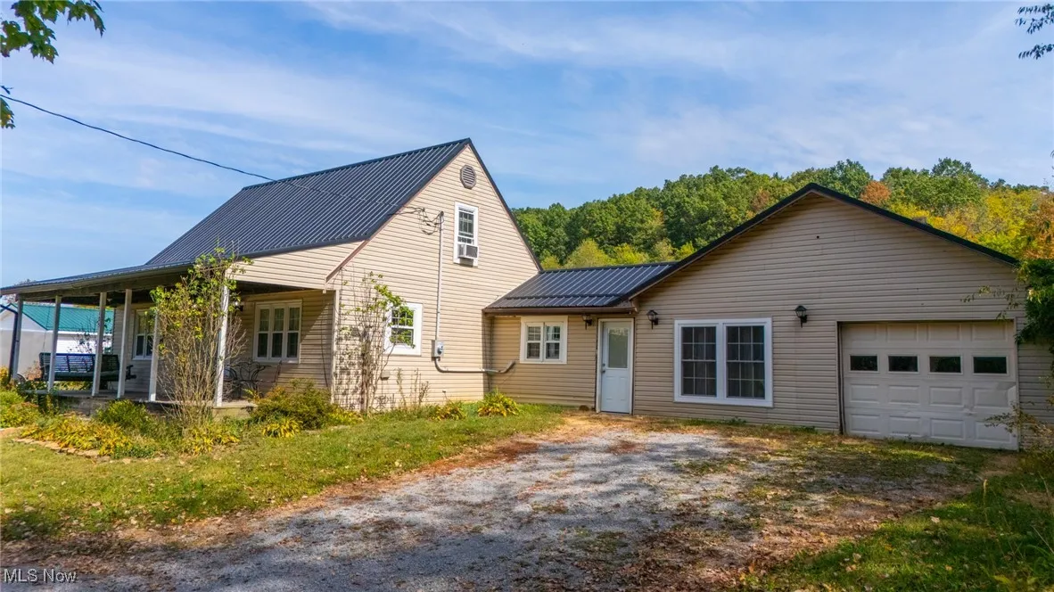 View of front of property with a metal roof, a standing seam roof, and driveway