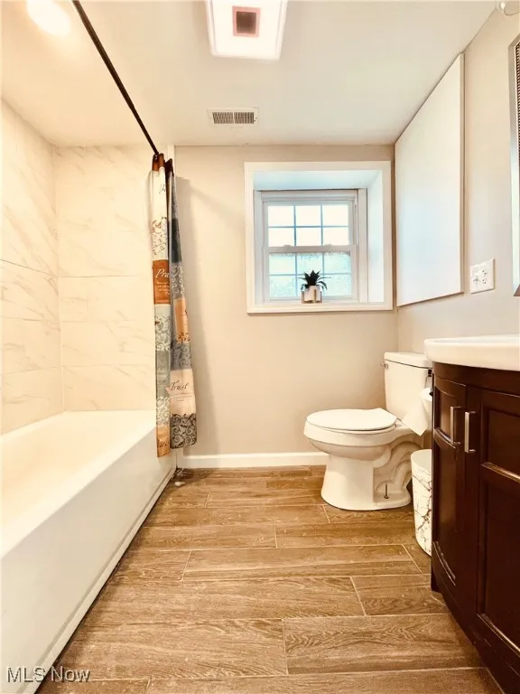Bathroom with shower / bathtub combination with curtain, vanity, and wood tiled floors