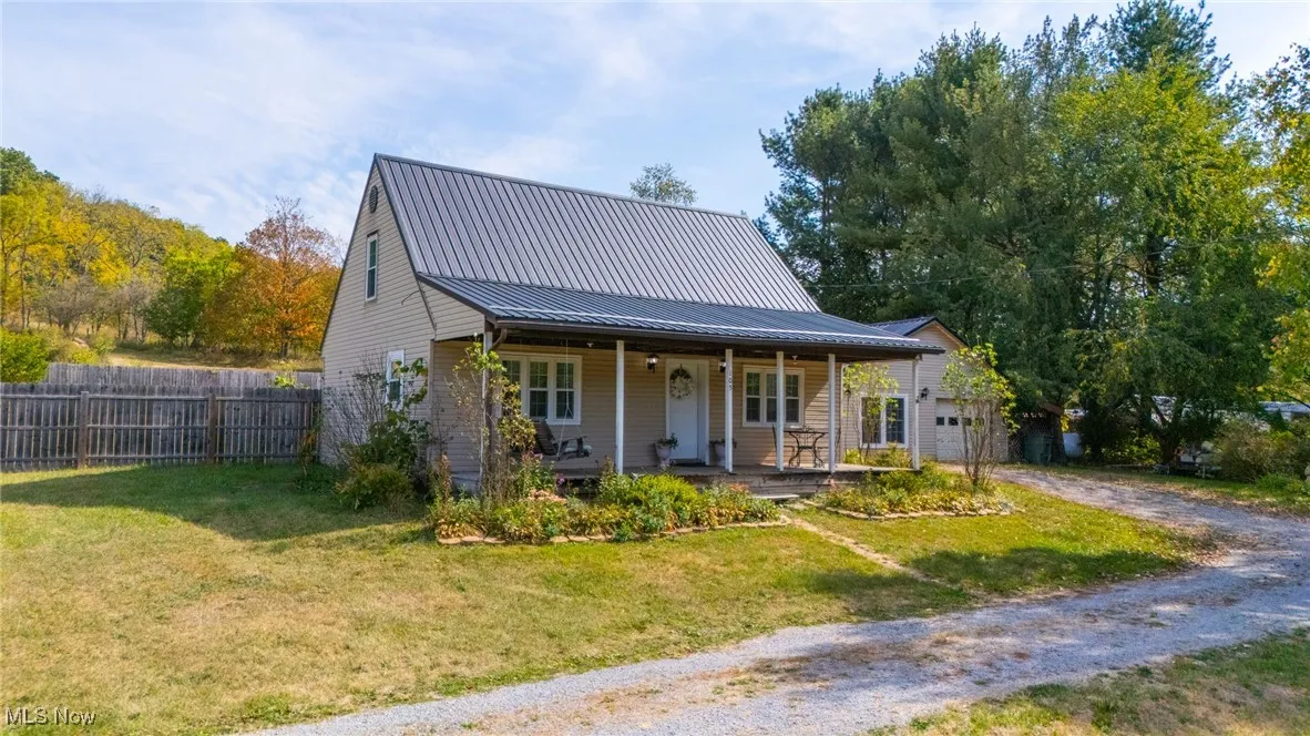 View of front of house with a porch, a metal roof, driveway, and an attached garage