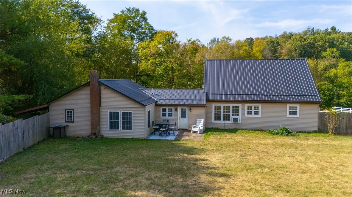 Back of house with a metal roof, a patio, a chimney, and a standing seam roof