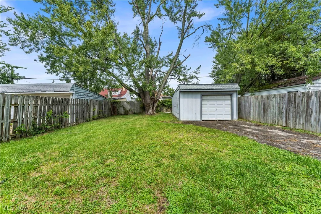Fenced backyard with an outbuilding, driveway, and a garage