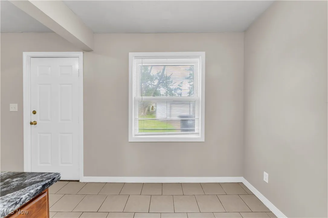 Entryway with light tile patterned flooring and baseboards