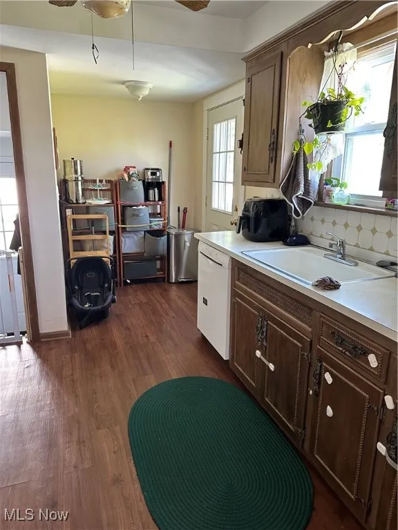 Kitchen featuring a ceiling fan, light countertops, and dark wood-style flooring