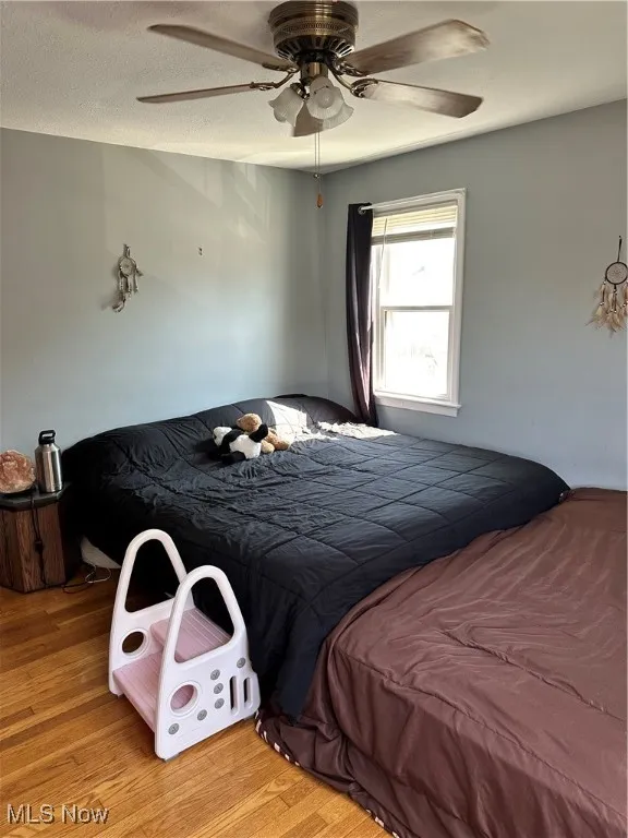 Bedroom with wood finished floors, a ceiling fan, and a textured ceiling