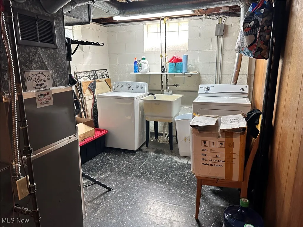 Washroom with dark flooring, washing machine and clothes dryer, and heating unit