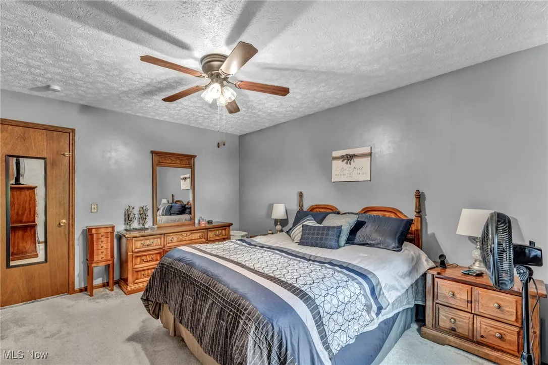 Bedroom with carpet floors, a textured ceiling, and a ceiling fan
