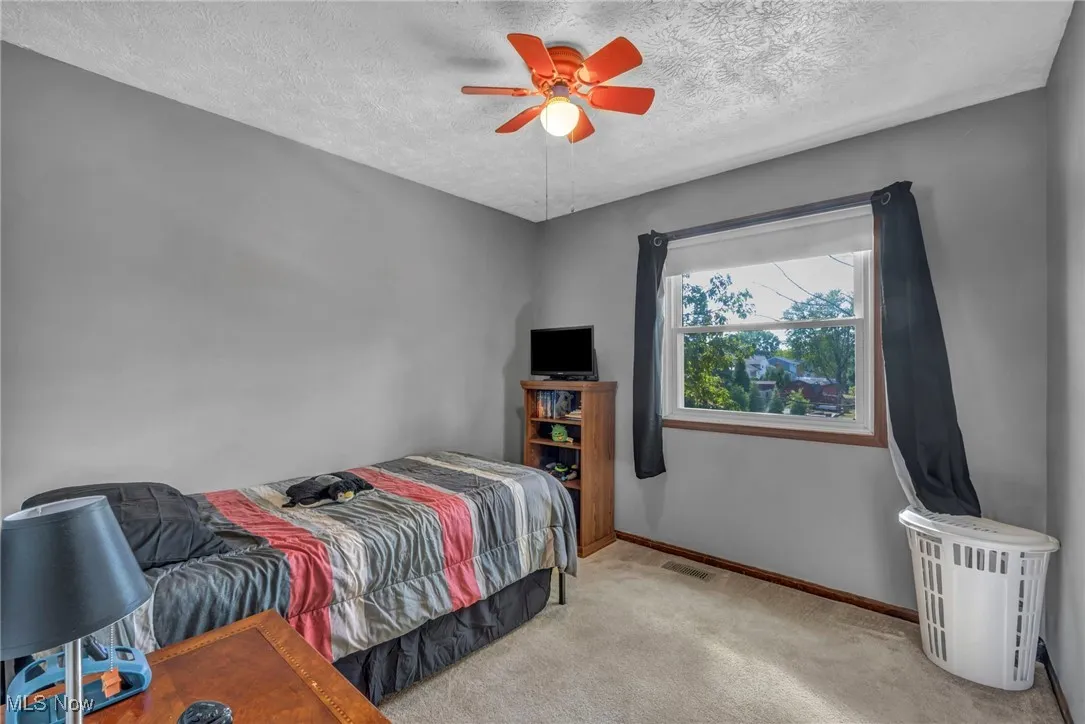 Carpeted bedroom with a textured ceiling and ceiling fan