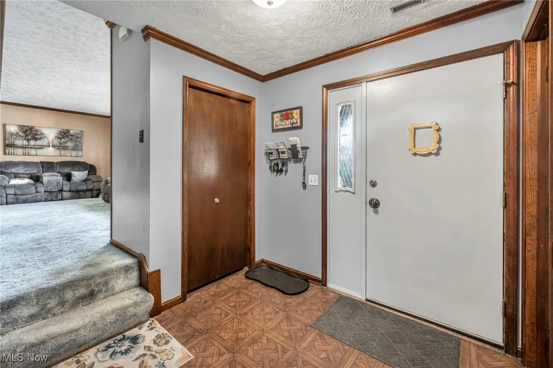 Entrance foyer featuring a textured ceiling and crown molding