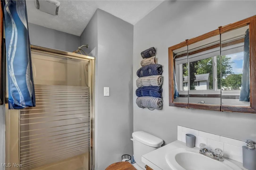 Bathroom with a shower stall, vanity, and a textured ceiling