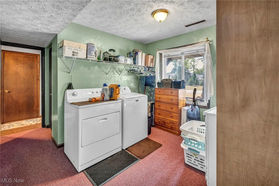 Laundry area featuring a textured ceiling, separate washer and dryer, and carpet floors