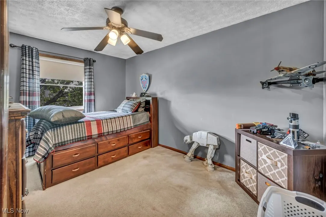 Carpeted bedroom featuring a textured ceiling and a ceiling fan