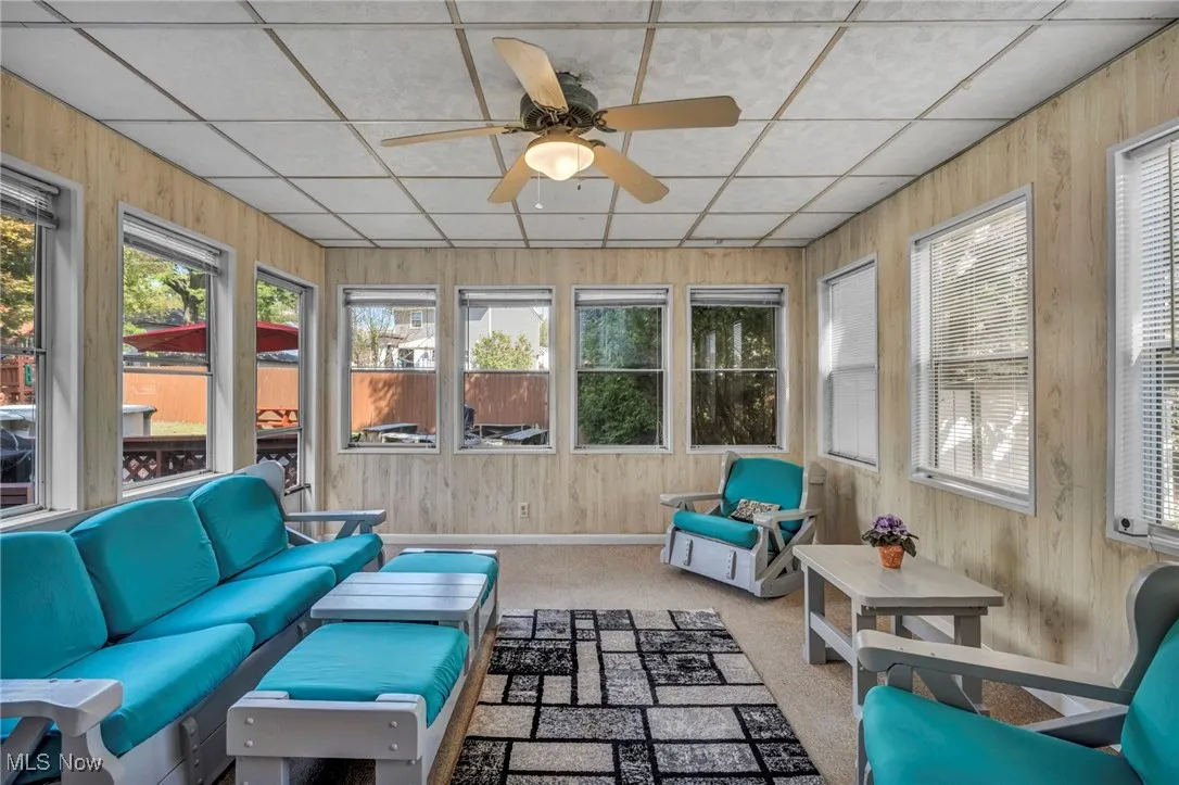 Sunroom / solarium featuring plenty of natural light, carpet, wooden walls, and a paneled ceiling