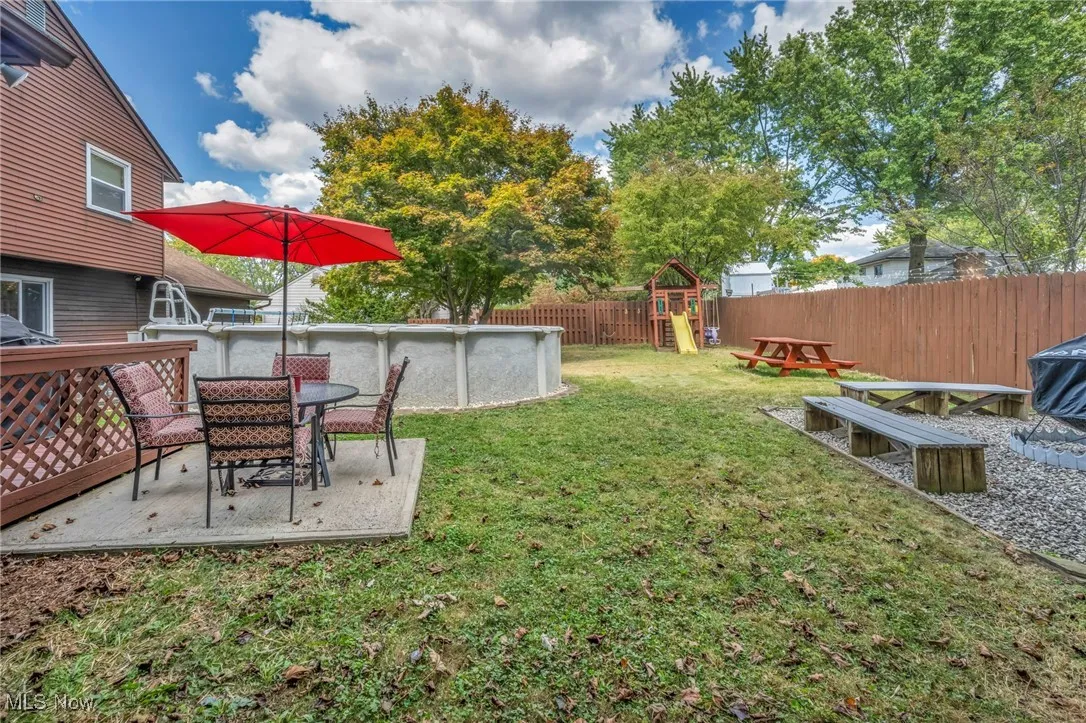 Fenced backyard with a playground and a patio