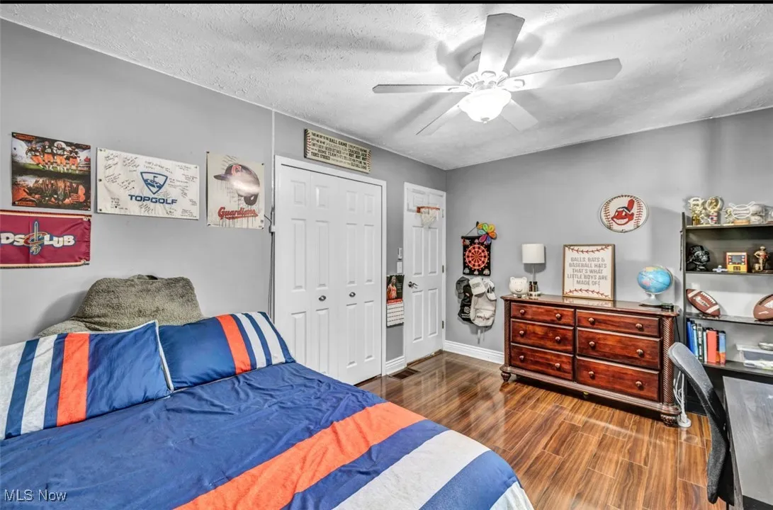 Bedroom featuring dark wood-type flooring, a textured ceiling, a closet, and ceiling fan