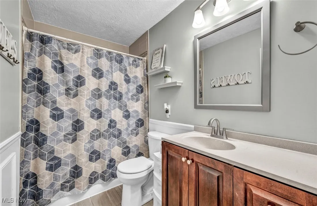 Full bathroom with vanity, a textured ceiling, and a shower with shower curtain