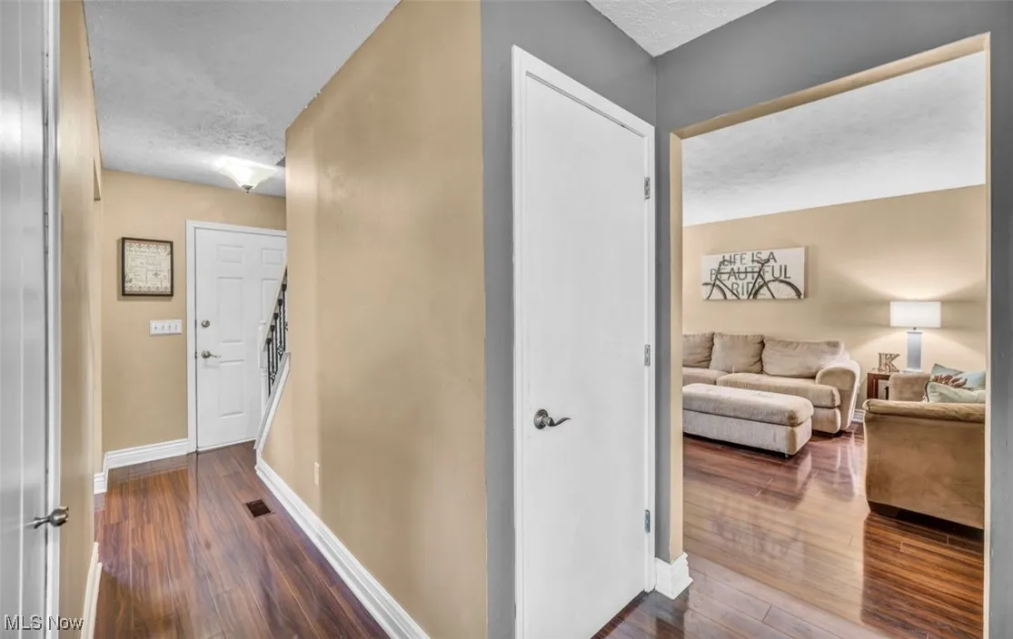 Hall featuring dark wood-style floors, a textured ceiling, and stairs