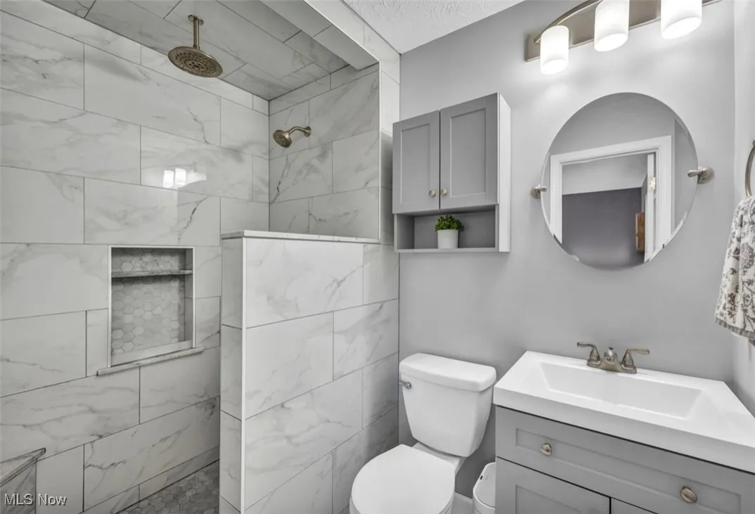 Bathroom featuring vanity, a walk in shower, and a textured ceiling