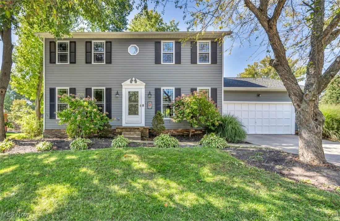 Colonial inspired home featuring concrete driveway, a front yard, and a garage
