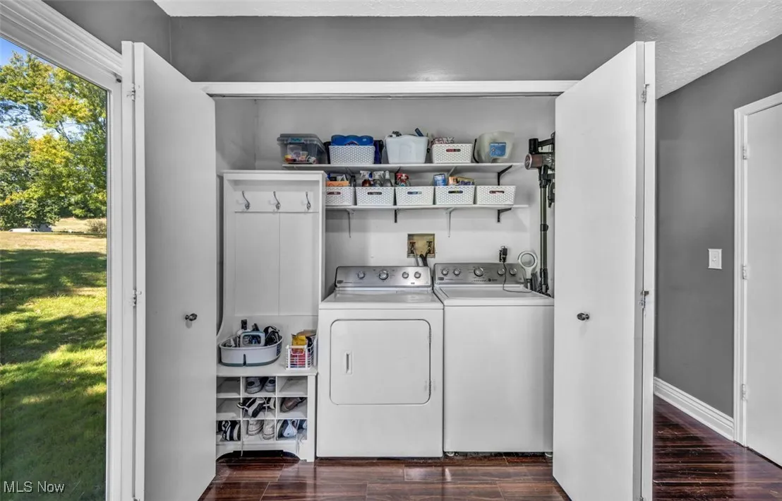 Laundry area with dark wood-style flooring, a textured ceiling, and washing machine and dryer