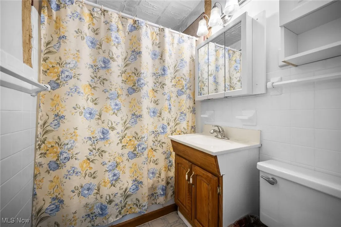 Bathroom with tile walls, vanity, curtained shower, and backsplash